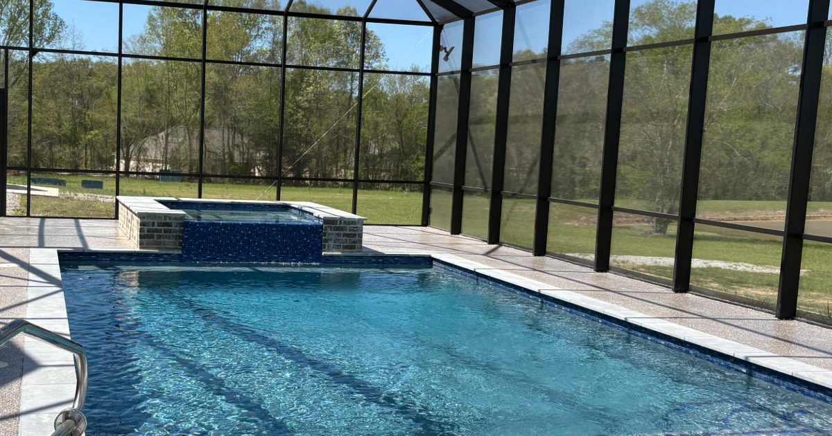 Indoor pool inside a glass-enclosed enclosure, with a raised spa at the far end and blue-tiled water.